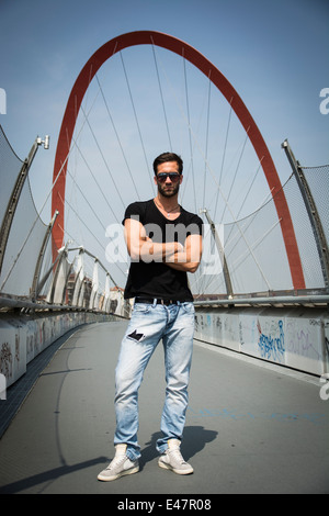 Bel giovane uomo in piedi all'aperto di fronte Arco Olimpico di Torino, Italia Foto Stock