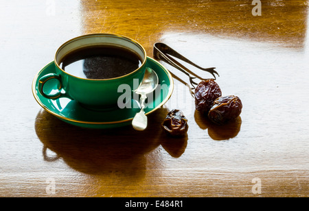 Una tazza di forte caffè nero con date e pinze Foto Stock