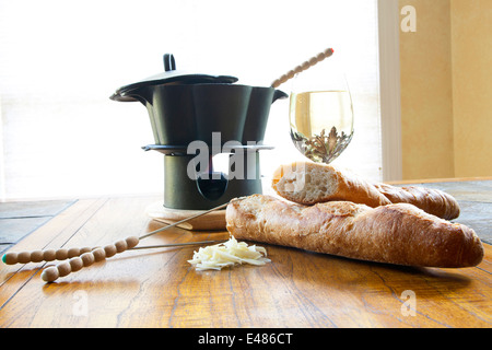 Ancora vita disposizione di fondue pot con spiedini, crosta di pane, formaggio e vino. Foto Stock