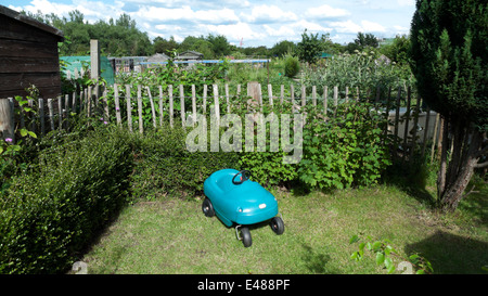 Un turchese in plastica del bambino vintage auto nel giardino sul retro di una casa confinante con appezzamenti con un picchetto recinto Londra UK KATHY DEWITT Foto Stock