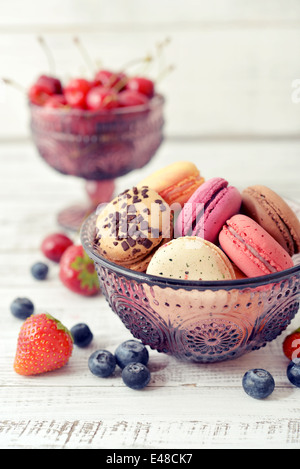 Diversi tipi di amaretti in vaso di vetro con frutti di bosco sulla luce sullo sfondo di legno Foto Stock