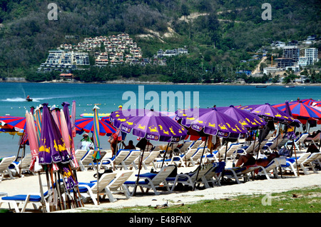 Città di patong / Phuket, Thailandia: la gente a prendere il sole sulla plastica sedie a sdraio sotto gli ombrelloni colorati a Patong Beach Foto Stock