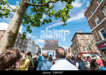 La gente guarda il Tour de France apertura sullo schermo in York con frecce rosse volando sopra la città Foto Stock