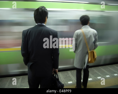 Tokyo pendolari attendere sulla piattaforma per è in arrivo un treno della metropolitana Foto Stock
