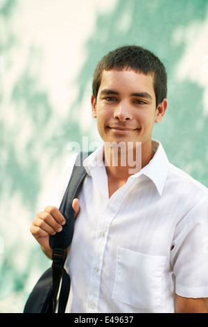Ritratto di giovane maschio ispanico studente sacco di contenimento e sorridente alla fotocamera a sorridere Foto Stock