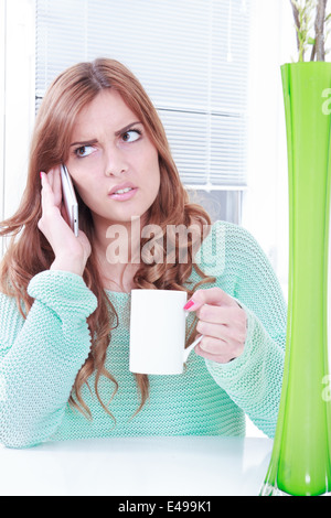 Preoccupato della donna la ricezione di cattive notizie su telefono, ragazza con tazza di caffè e telefono cellulare con reazione negativa Foto Stock