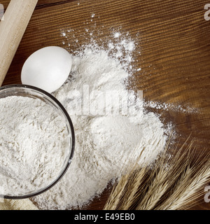 Preparare gli ingredienti per la cottura. Farina, uova su un tavolo di legno. spikelets di grano Foto Stock