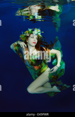 Una giovane donna con grandi capelli in posa di un subacqueo in piscina Foto Stock
