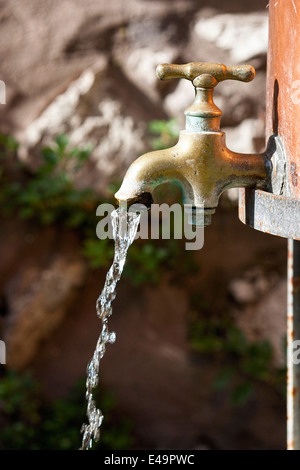 Acqua che scorre da un vecchio rubinetto in ottone Foto Stock