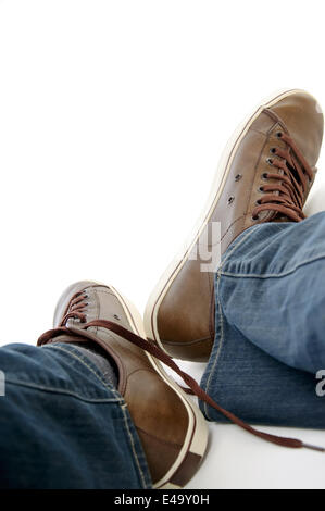 Gambe maschio in marrone scarpe da ginnastica e jeans Foto Stock