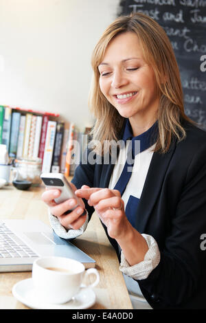 Imprenditrice tramite cellulare in Cafe Foto Stock