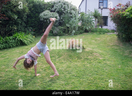 Un figlio di 11 anni ragazza cartwheels pratiche in giardino Foto Stock