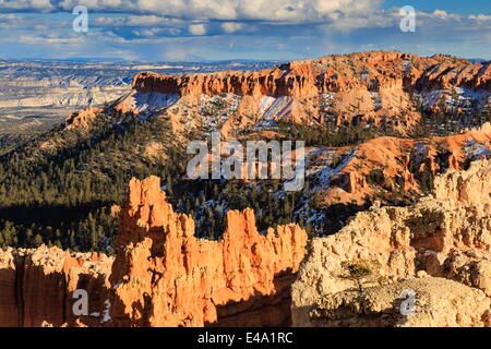 Nel tardo pomeriggio sole illumina hoodoos e rocce attraverso un cielo nuvoloso in inverno, Sunset Point, Parco Nazionale di Bryce Canyon, Utah, Stati Uniti d'America Foto Stock