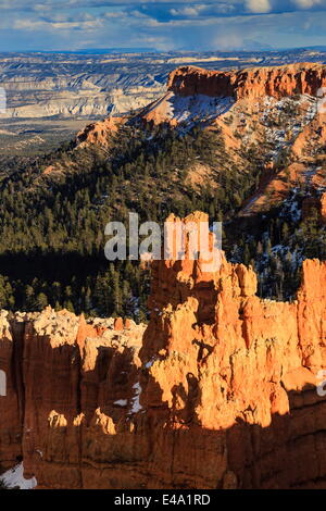 Nel tardo pomeriggio sole illumina hoodoos e rocce attraverso un cielo nuvoloso in inverno, Sunset Point, Parco Nazionale di Bryce Canyon, Utah, Stati Uniti d'America Foto Stock