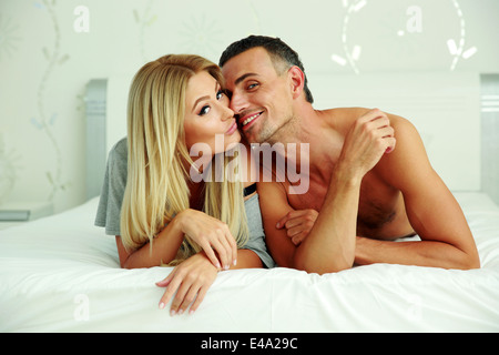 Amorevole coppia giovane sdraiato sul letto di casa Foto Stock