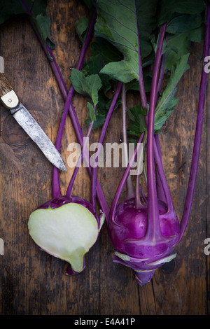 Intero e una metà blu cavoli rapa, Brassica oleracea var. gongylodes L. e un coltello sul legno scuro, vista in elevazione Foto Stock