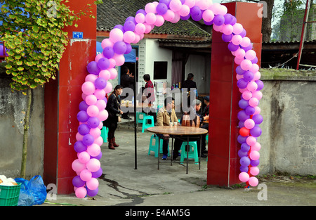 PENGHZOU, CINA: una ghirlanda di fiori di rosa e viola ballons circonda un agriturismo porta ad un pranzo di nozze party Foto Stock