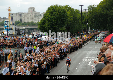 London, Regno Unito - 7 Luglio 2014: Tour de France straggler sfocia nella immensa folla festante sul terrapieno dietro il peloton principale. Foto Stock