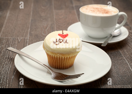 Una tortina guarnita con crema di burro la glassa con il messaggio "ti amo" , servita con un cappuccini, studio shoot Foto Stock