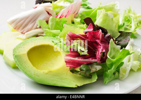 Ingrandimento di una piastra con una rinfrescante insalata mista con foglie di insalata di avocado e cetrioli Foto Stock