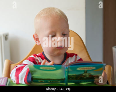 Un giovane ragazzo bambino la lettura di un libro Foto Stock