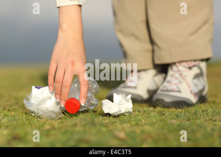 Eco escursionista lato raccogliere rifiuti in erba della montagna Foto Stock