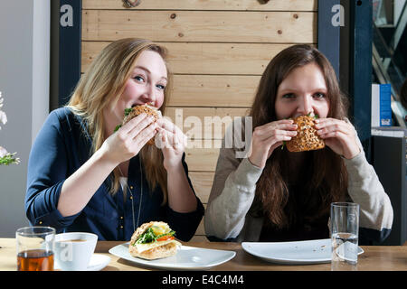 Due giovani donne mangiando panini in un cafe Foto Stock