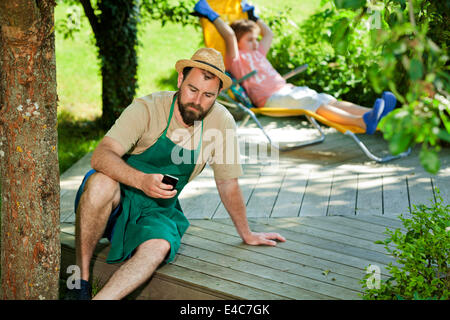 L'uomo utilizza lo smartphone, ragazzo rilassante in background, Monaco di Baviera, Germania Foto Stock