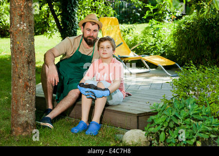 Padre e figlio di prendere una pausa nel giardino, Monaco di Baviera, Germania Foto Stock