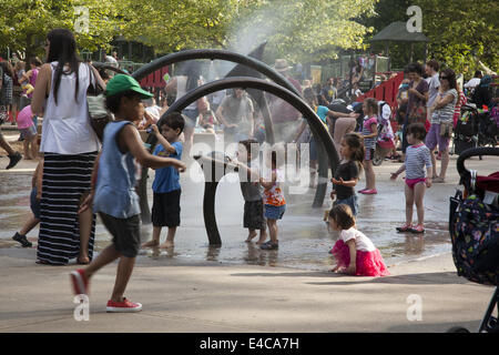 Bambini rinfrescarvi con l'acqua le irroratrici a Xi San Parco Giochi nel Prospect Park di Brooklyn, New York. Foto Stock