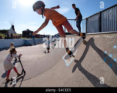 Ragazzo giovane su uno skateboard scendendo half-pipe, Bude, Cornwall, Regno Unito Foto Stock