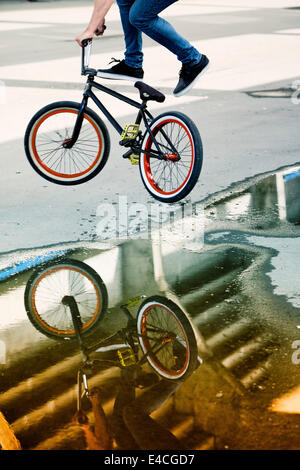 Riflessioni in una pozza di BMX biker eseguendo uno stunt Foto Stock