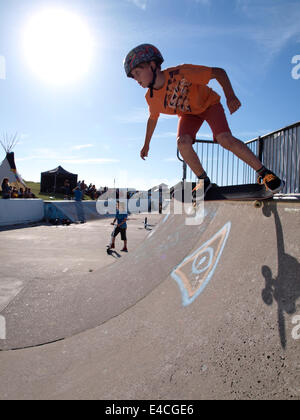 Ragazzo giovane su uno skateboard scendendo half-pipe, Bude, Cornwall, Regno Unito Foto Stock