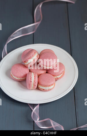 Rosa macarons con crema di burro al riempimento sulla piastra bianca Foto Stock