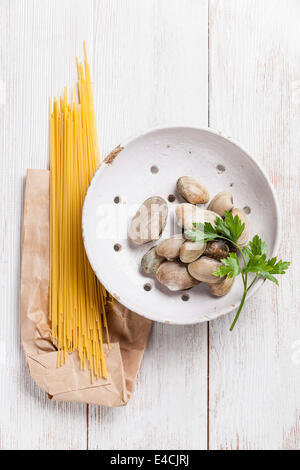 Materie gusci vongole e materie sapaghetti per la cottura della pasta vongole in bianco sullo sfondo di legno Foto Stock