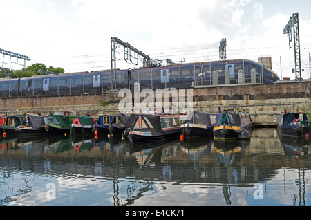 Un treno Eurostar passa a fianco di canal imbarcazioni sul Regent's Canal in King Cross a Londra. Foto Stock