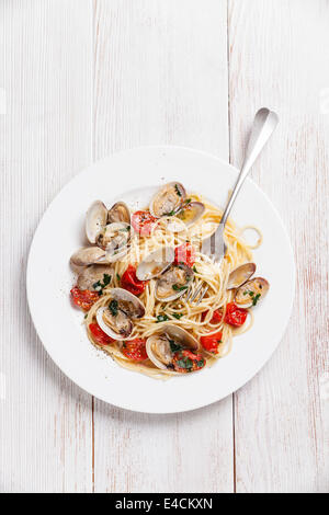 Piatti di pasta con le vongole in salsa di pomodoro Spaghetti vongole in bianco sullo sfondo di legno Foto Stock