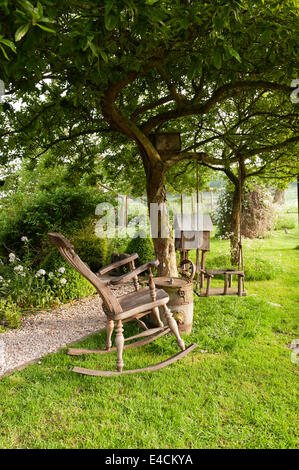 In legno sedia a dondolo e oscillante nel giardino del cottage del paese Foto Stock