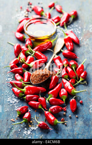 Red Hot Chili Peppers e olio di oliva su sfondo di legno - cottura o cibo piccante concetto Foto Stock