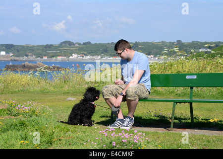 Uomo seduto su un banco di lavoro con cane Cockapoo Foto Stock