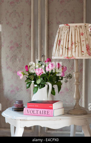 Ruched ombra di Kate Forman sul piccolo tavolo in legno con caraffa di rose e Voltaire prenota Foto Stock
