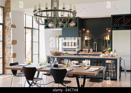 Verdigris lampadario pende al di sopra di una quercia sormontata tavolo da pranzo in cucina con unità dipinte di blu/grigio Foto Stock