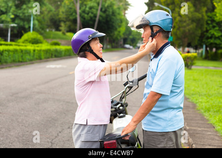 Nonna felice di aiutare il nonno di indossare un casco Foto Stock