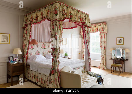 Letto Fourposter con chintz tende in camera da letto con chaise. Un disegno di Romney è appeso sopra il tavolo Foto Stock