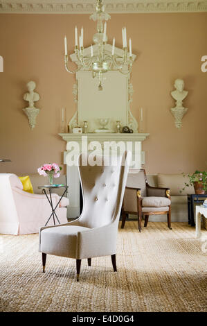 Ala sedia imbottita in Veere Grenney Tempio tessuto in grand salon con lampadario in vetro e busti decorativi Foto Stock
