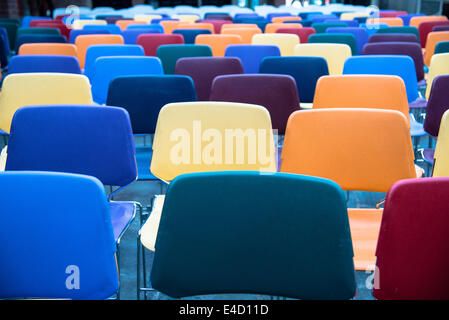 Righe di colorati e svuotare le sedie in plastica in una scuola Foto Stock