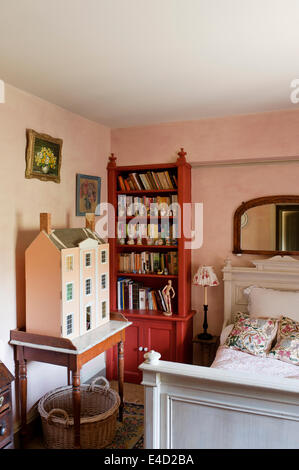 Vecchia casa delle bambole sul piano di marmo lavandino in camera da letto con il libro rosso di ripiano e bianco letto in legno Foto Stock