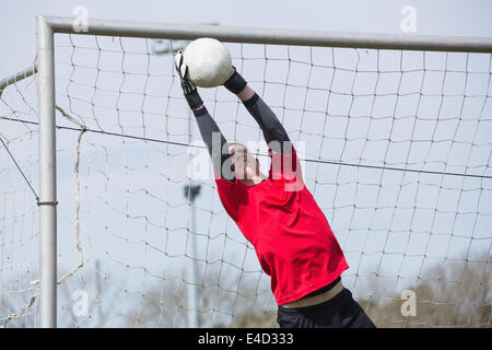 Il portiere in rosso il salto per salvare un obiettivo Foto Stock