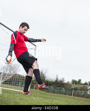 Il portiere in rosso calci palla lontano da obiettivo Foto Stock