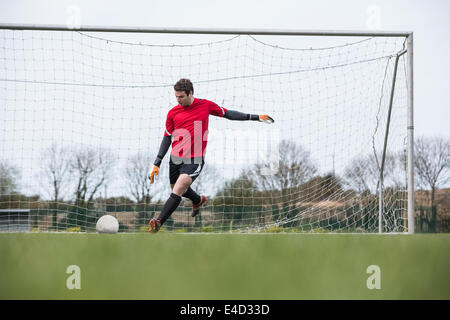 Il portiere in rosso calci palla lontano da obiettivo Foto Stock